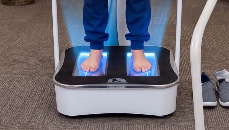 Bare feet on a lit 3D foot scanner plate during a Foot Levelers scan