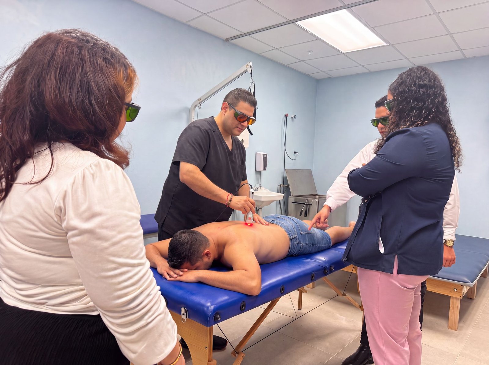Dr. Tim Bhakta treating a patient’s back with Class IV laser therapy, everyone wearing protective eyewear